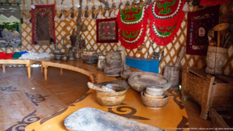 A central hearth, low furnishings, carpets, and bright wall hangings fill the interior