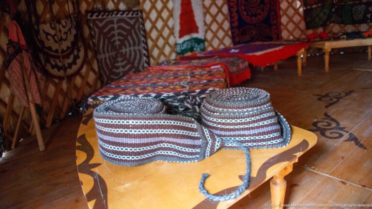 Round patterned cushions rest on a low table inside the yurt