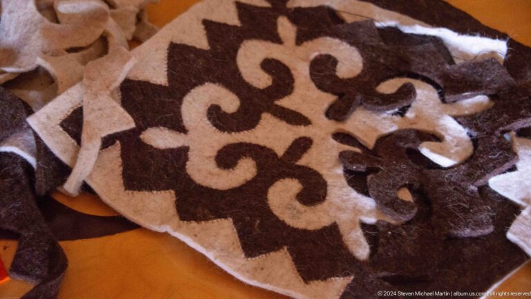 Cut felt sections with mirrored scrolling motifs are arranged for assembly