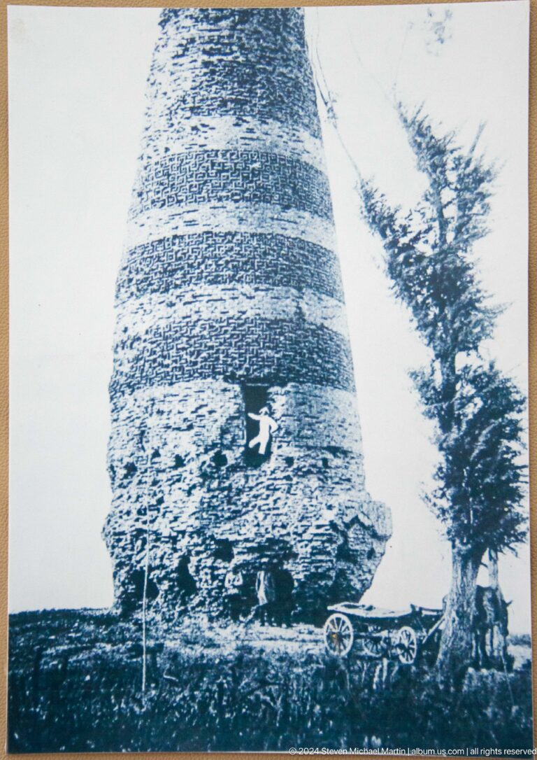 A black-and-white historical image shows the tower before modern restoration