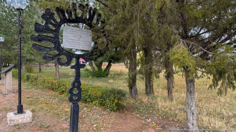 A metal plaque stands beside a path in the archaeological grounds