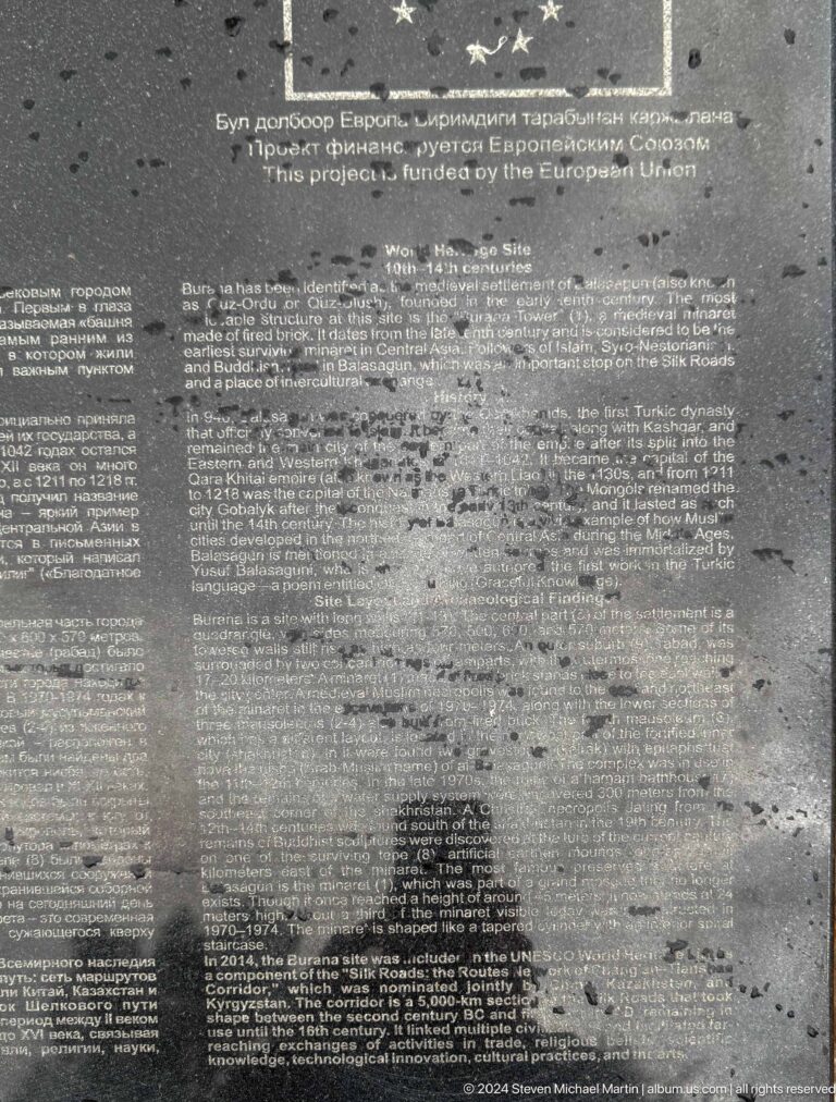 Dense text is engraved across a broad dark stone or metal surface