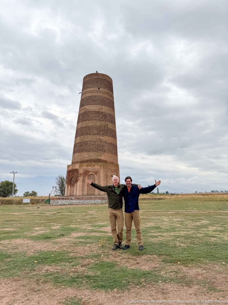 A visitor raises both arms in front of the tower