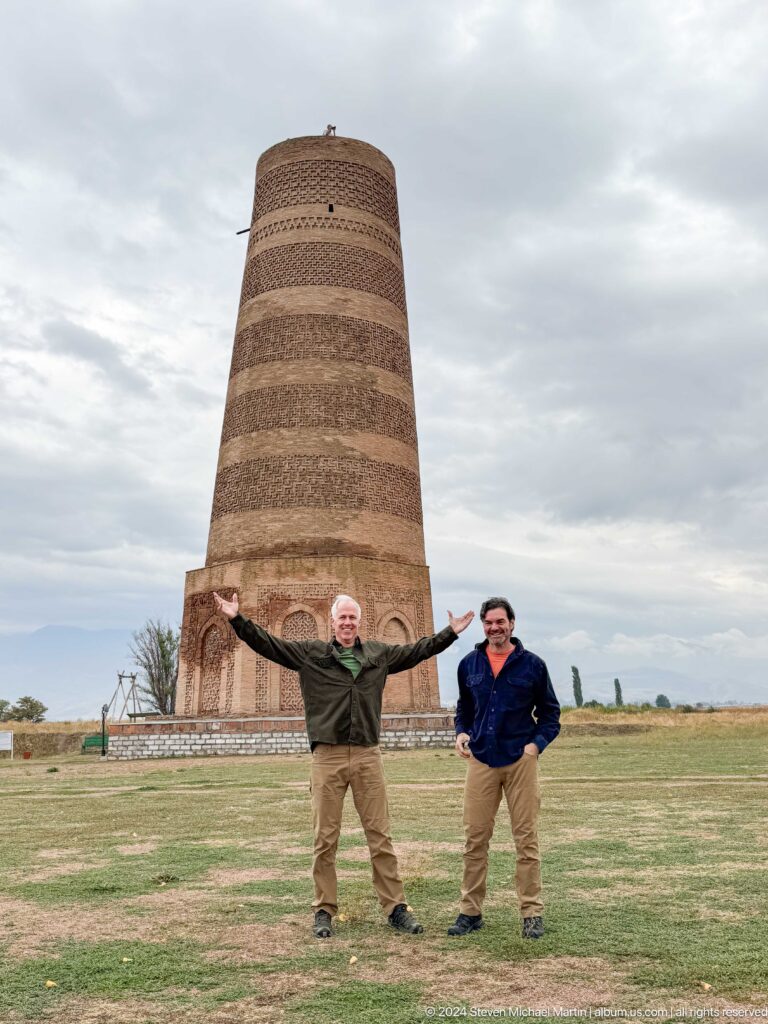 Two visitors stand in the foreground with the tower rising behind them