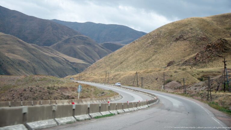Winding paved road through brown mountain slopes.