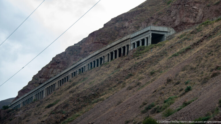 Covered railway gallery cut into a steep slope.