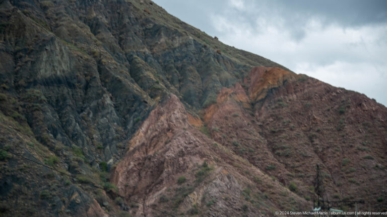 Layered rocky mountain gorge under cloudy sky.