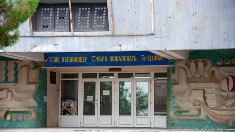 Entrance doors beneath a blue cyrillic sign.