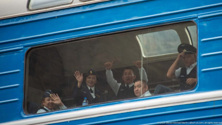 Passengers waving through train windows.