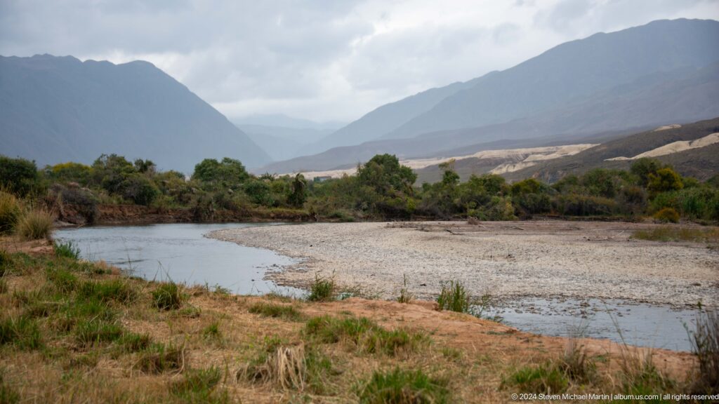 Broad gravel-bed river beneath misty layered mountains.