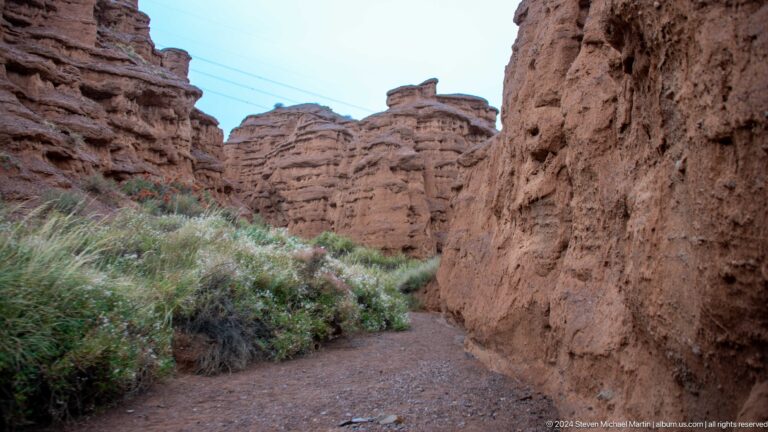 Narrow trail between high red eroded walls.