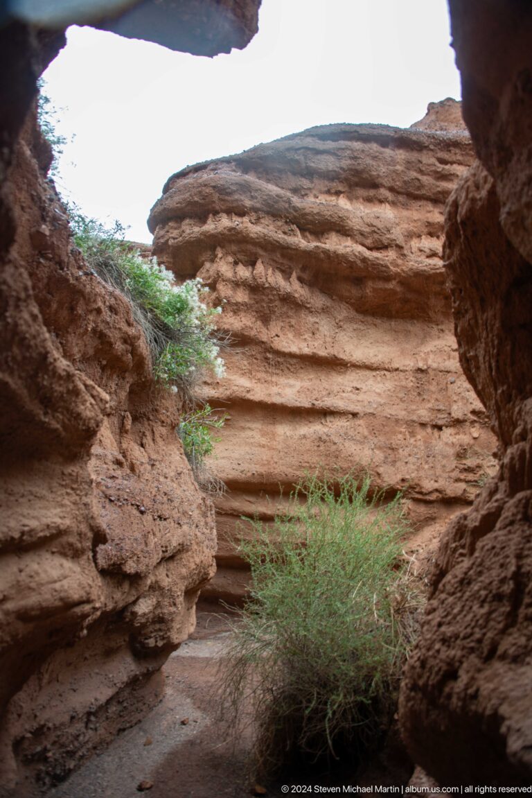 Rounded opening through layered red canyon wall.