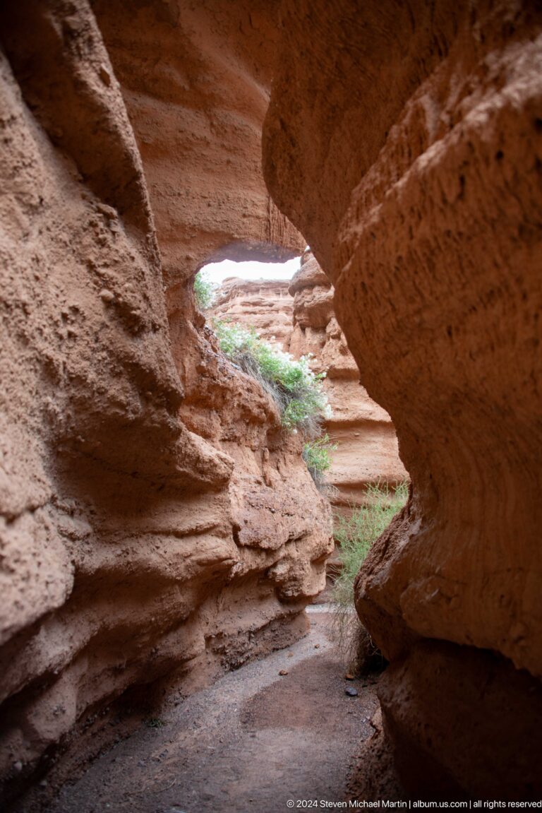 View through adjoining natural openings in red sediment.