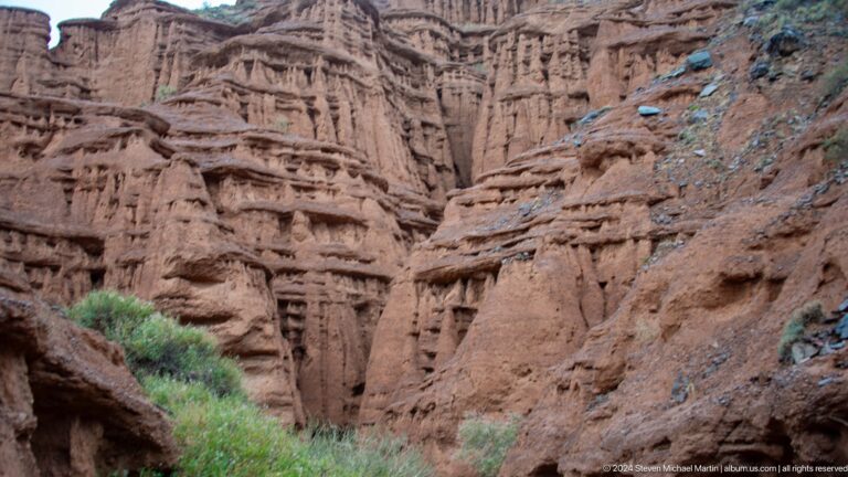 High ribbed canyon wall above a green floor.