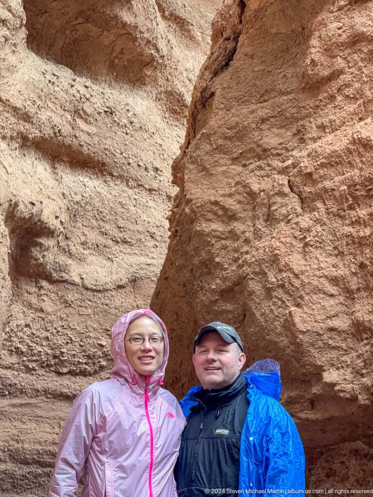 Two visitors partially visible at bottom of red canyon wall.