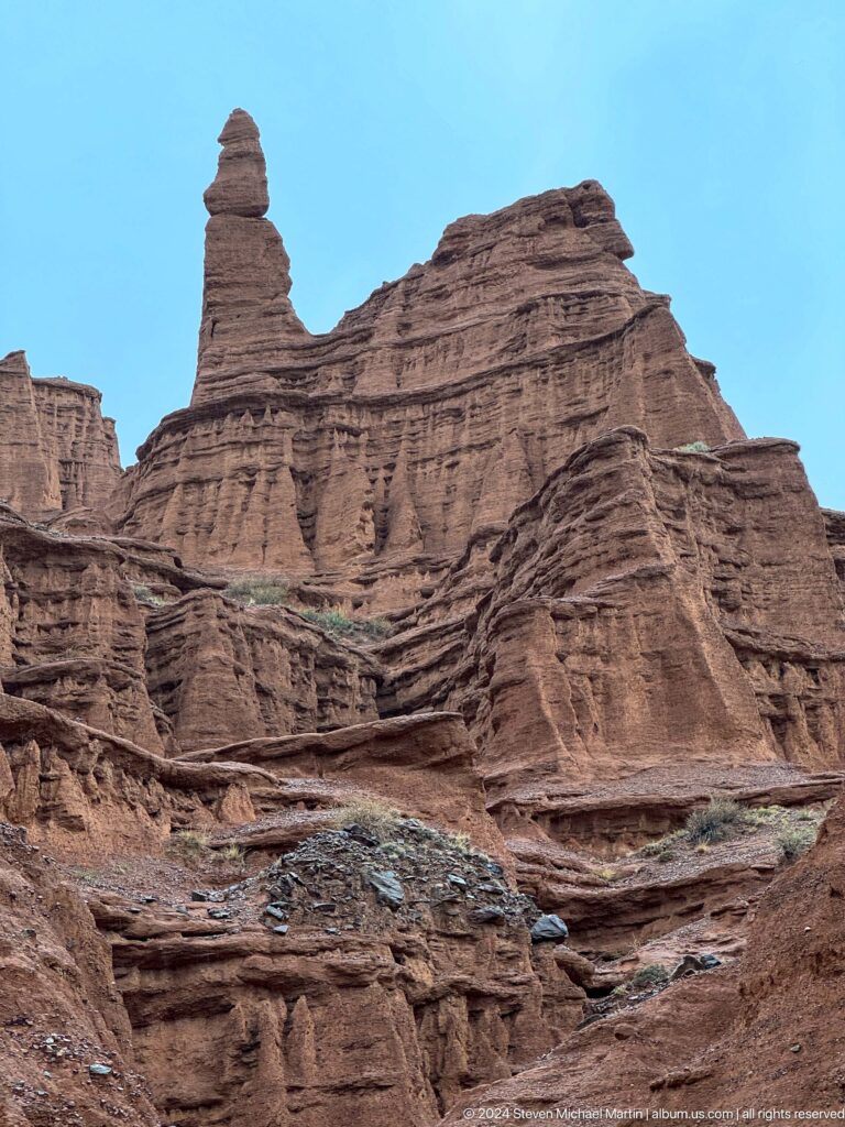 Monumental fluted red cliff rising steeply overhead.