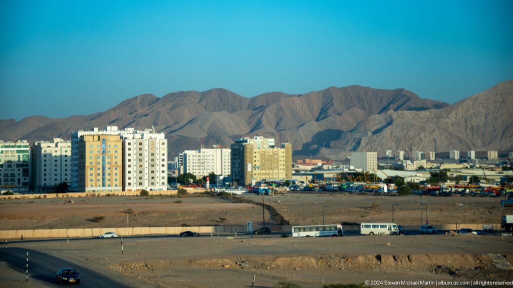 Urban buildings at foot of rugged brown mountains in Muscat, Oman.