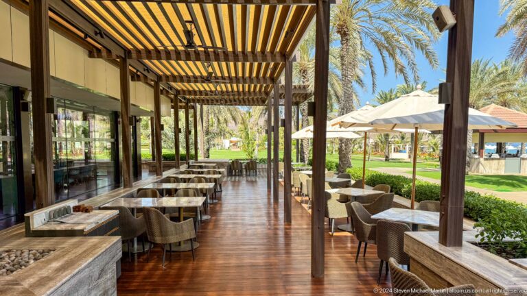 Shaded open-air restaurant beside garden in Muscat, Oman.