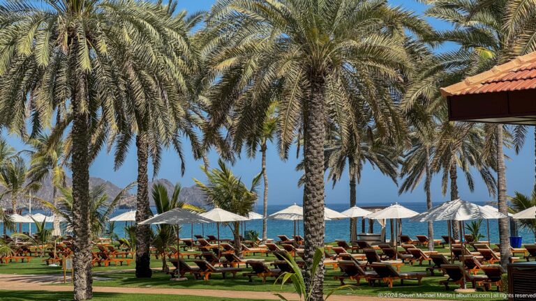 Beachfront lawn and palms with sea beyond in Muscat, Oman.