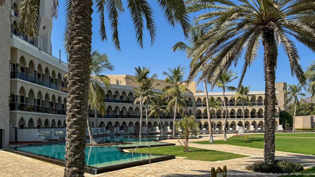 Palace-like resort courtyard with pool and palms in Muscat, Oman.