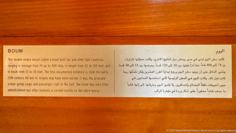 Bilingual museum text panel on orange wall in Muscat, Oman.