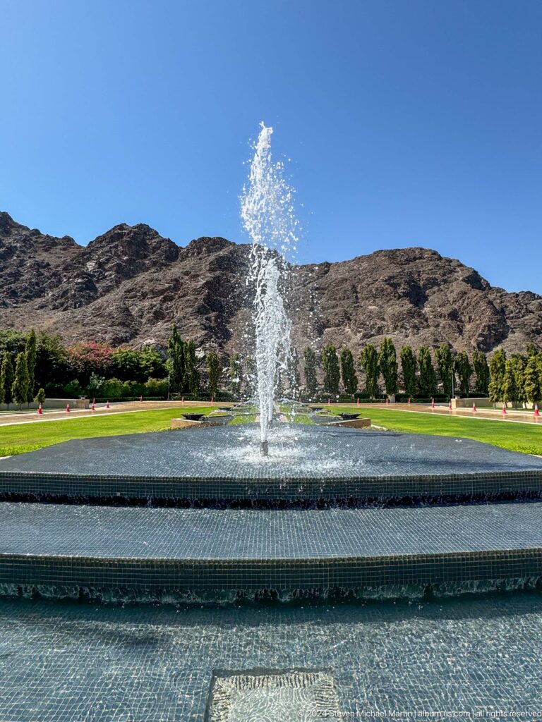 Fountain and formal lawn beneath mountains in Muscat, Oman.
