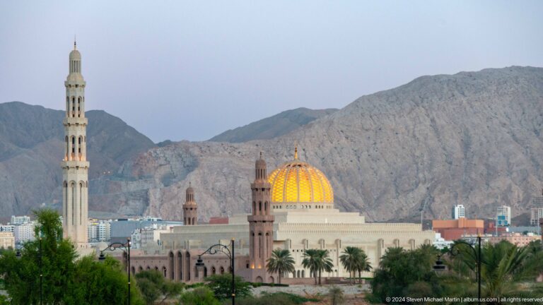 Golden dome and minaret before mountain ridge in Muscat, Oman.