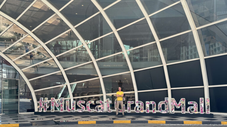 Glass-fronted building with hashtag Muscat and Mall sign in Muscat, Oman.
