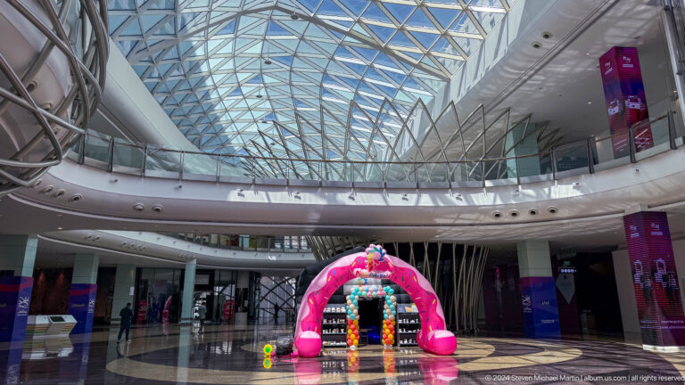Bright shopping mall atrium beneath glass roof in Muscat, Oman.