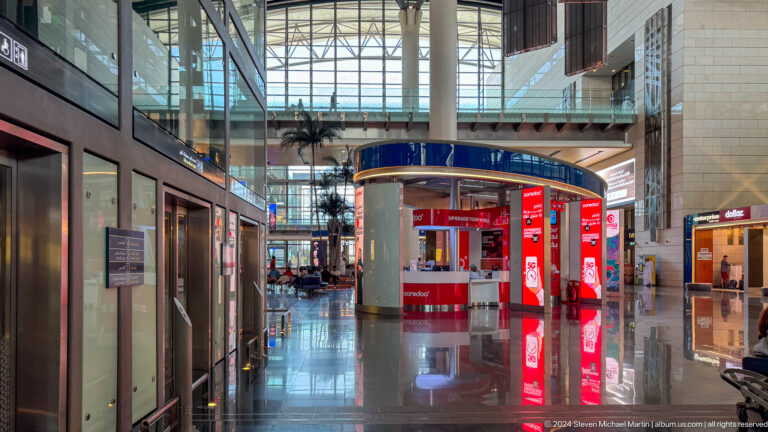 Red kiosk in glass-roofed retail corridor in Muscat, Oman.