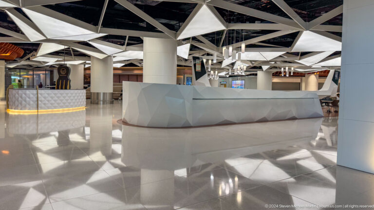 White airport check-in counters beneath exposed roof in Muscat, Oman.