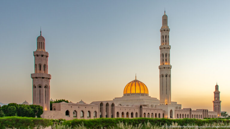 Gold dome and twin minarets above landscaped foreground in Muscat, Oman.