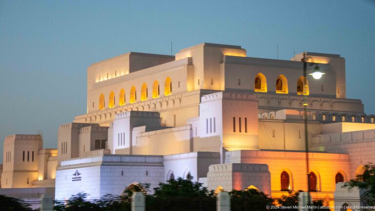 Large illuminated pale building with stepped massing in Muscat, Oman.