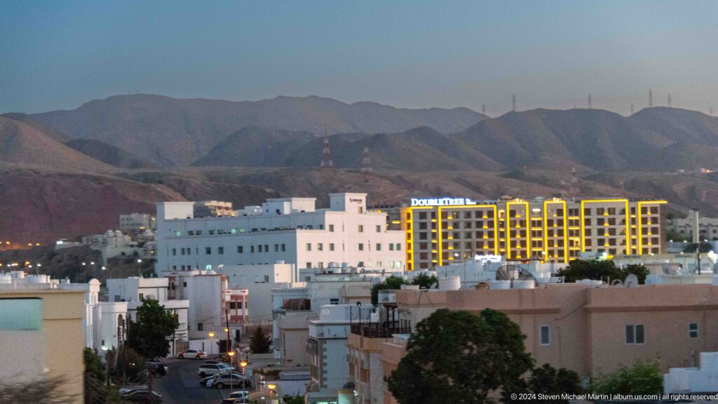 White low-rise city and hotels before rocky mountains in Muscat, Oman.