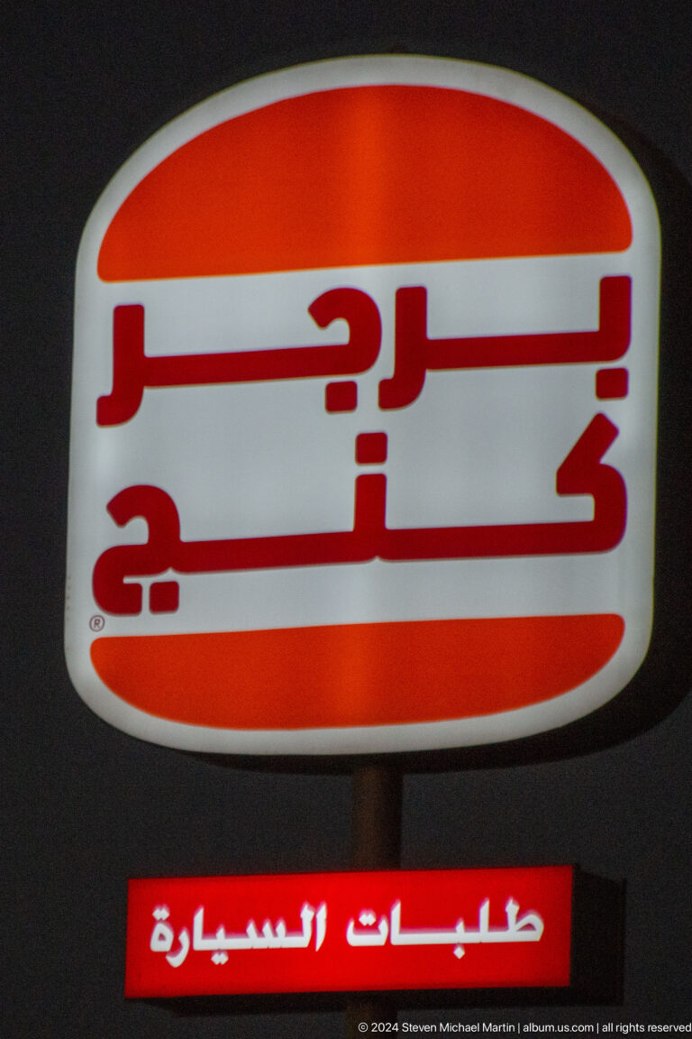 Red Arabic and English sign cropped at close range in Muscat, Oman.