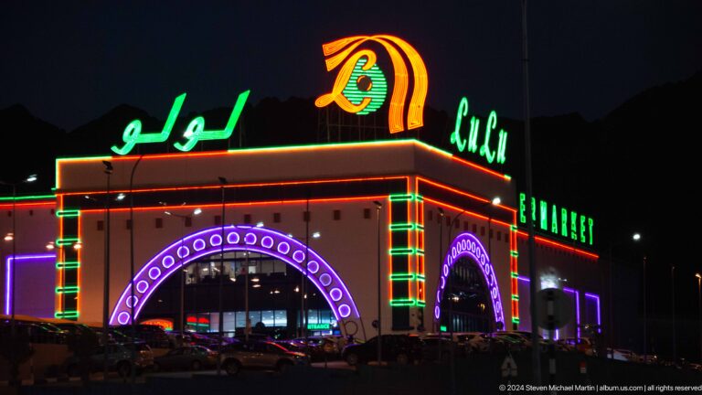 Neon amusement entrance with Arabic and English lettering in Muscat, Oman.