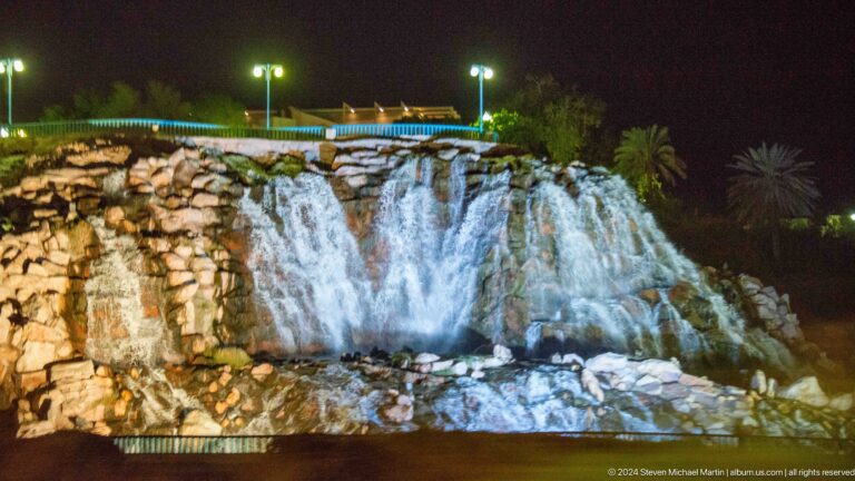 Illuminated artificial waterfall on rocky slope in Muscat, Oman.