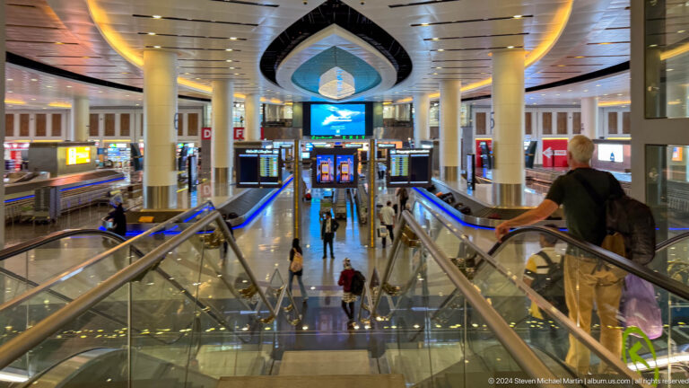 Shopping mall atrium with escalators and decorative arch in Muscat, Oman.