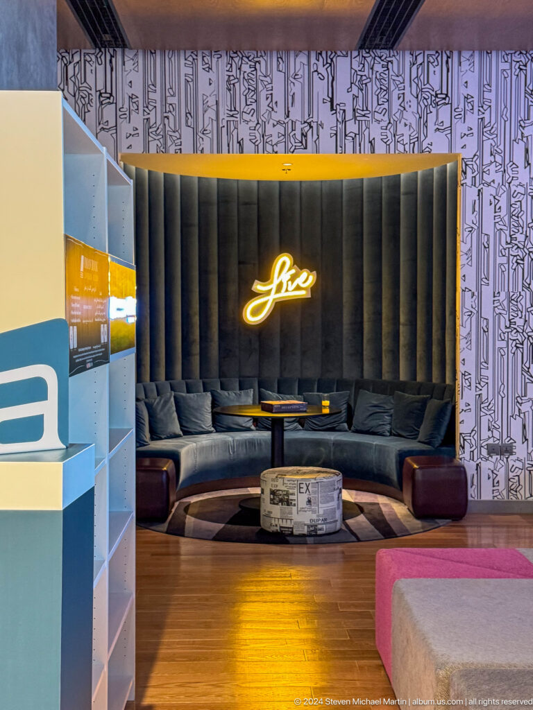 Dark lounge alcove with glowing gold script logo in Muscat, Oman.