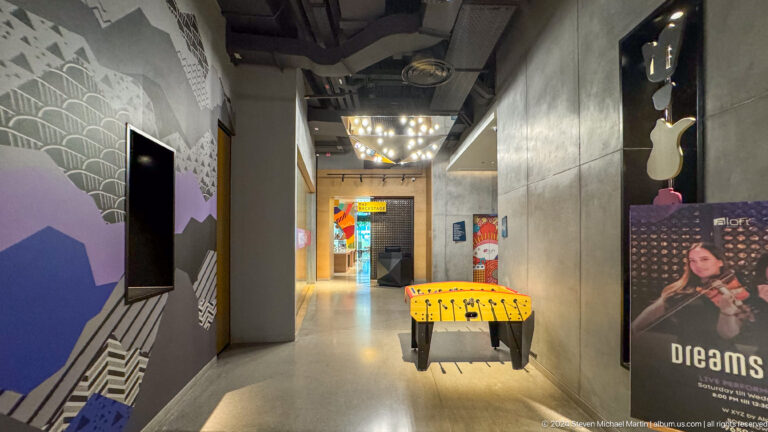 Industrial-style corridor with yellow bench and colorful art in Muscat, Oman.