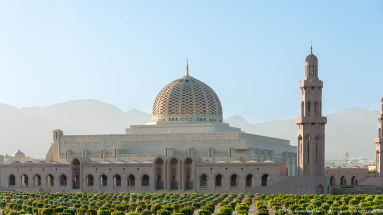 Large white mosque with ribbed dome and minaret in Muscat, Oman.