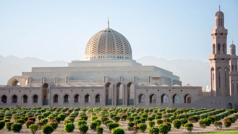 Sultan Qaboos Grand Mosque behind flower beds in Muscat, Oman.