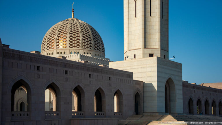 Dome and shadowed arcade beside minaret base in Muscat, Oman.