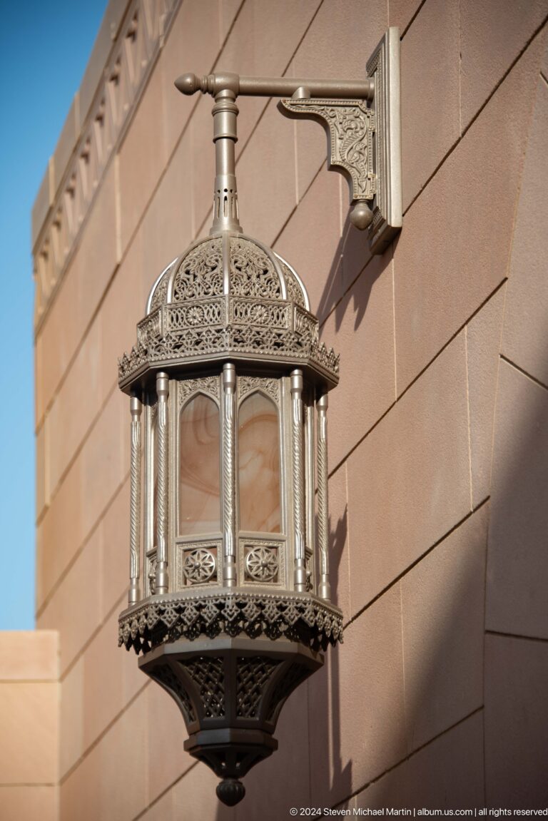 Ornate hanging lantern against pale wall in Muscat, Oman.