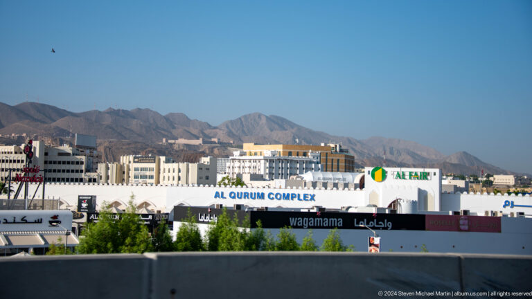 Sports complex and signage before mountains in Muscat, Oman.