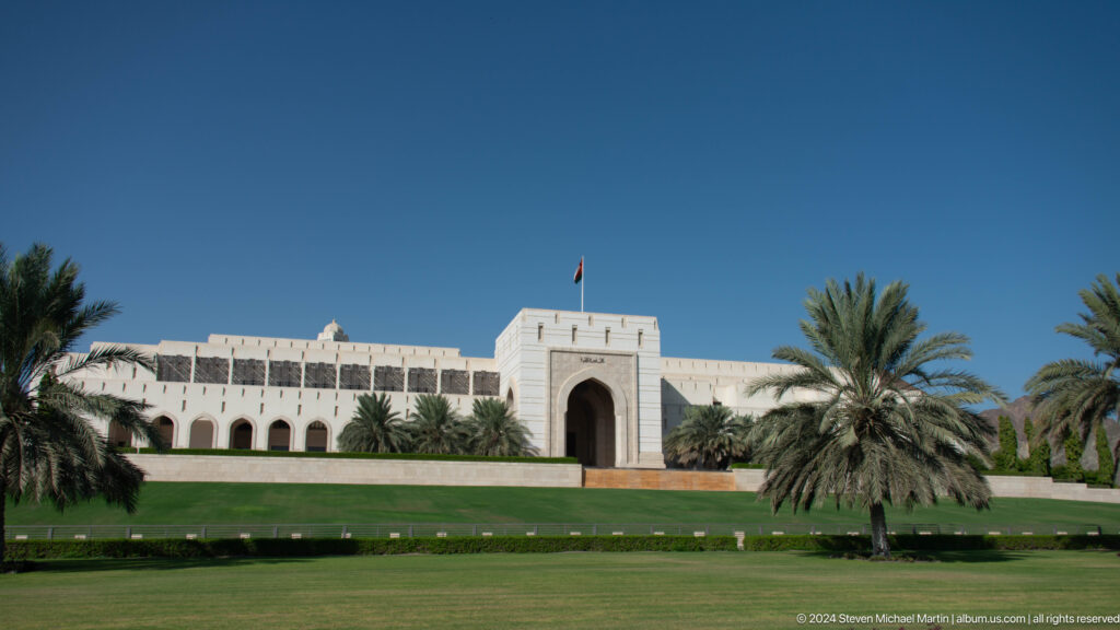 Long white government building beyond lawn in Muscat, Oman.