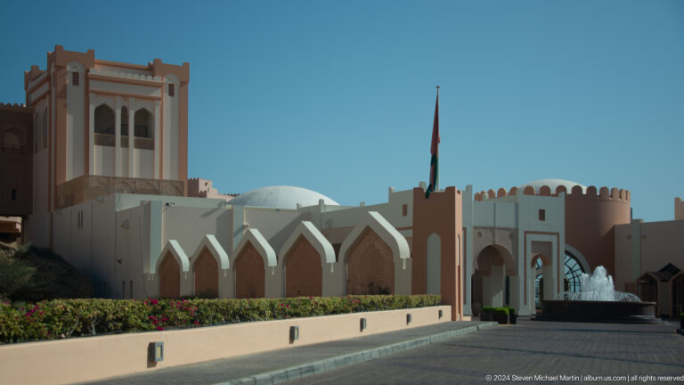 White ceremonial gateway with Omani flag in Muscat, Oman.
