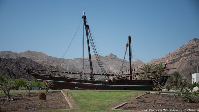 Traditional wooden dhow displayed on land in Muscat, Oman.