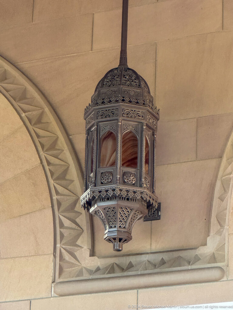 Ornate hanging lantern beneath decorated arch in Muscat, Oman.