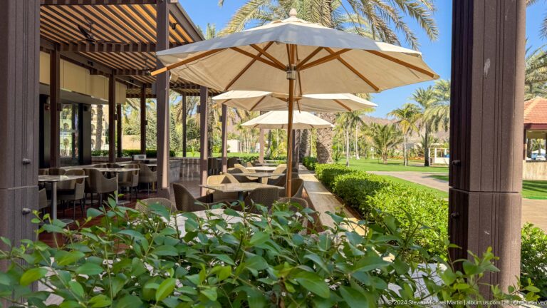 Shaded garden restaurant with umbrellas and greenery in Muscat, Oman.